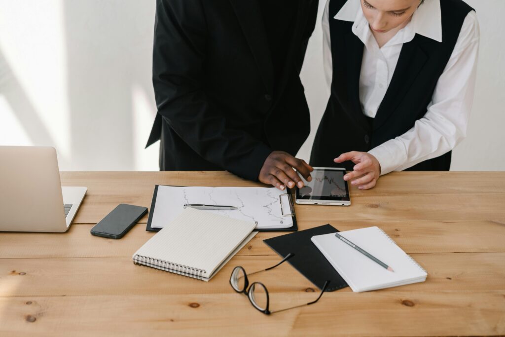 Two professionals collaborating over charts and tablet in a modern office setting.